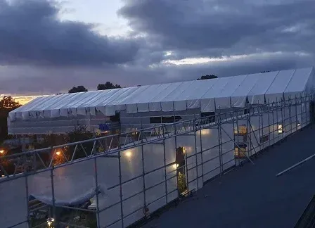 Vitt väderskyddstak över byggnaden mot skymningshimmel.